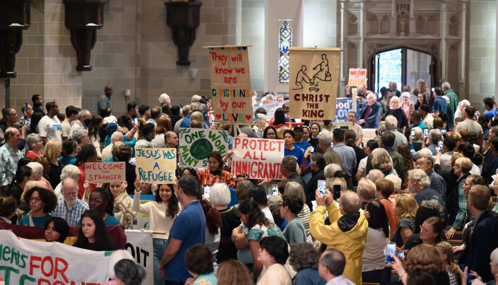 People of faith gathered with signs welcoming immigrants